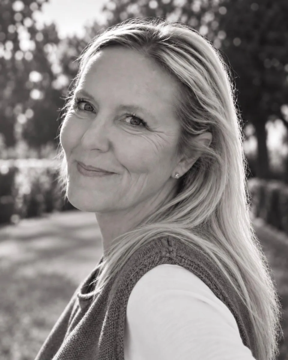 Sabrina, fondatrice de Rituels Douceur, sourit dans une allée arborée, en noir et blanc.